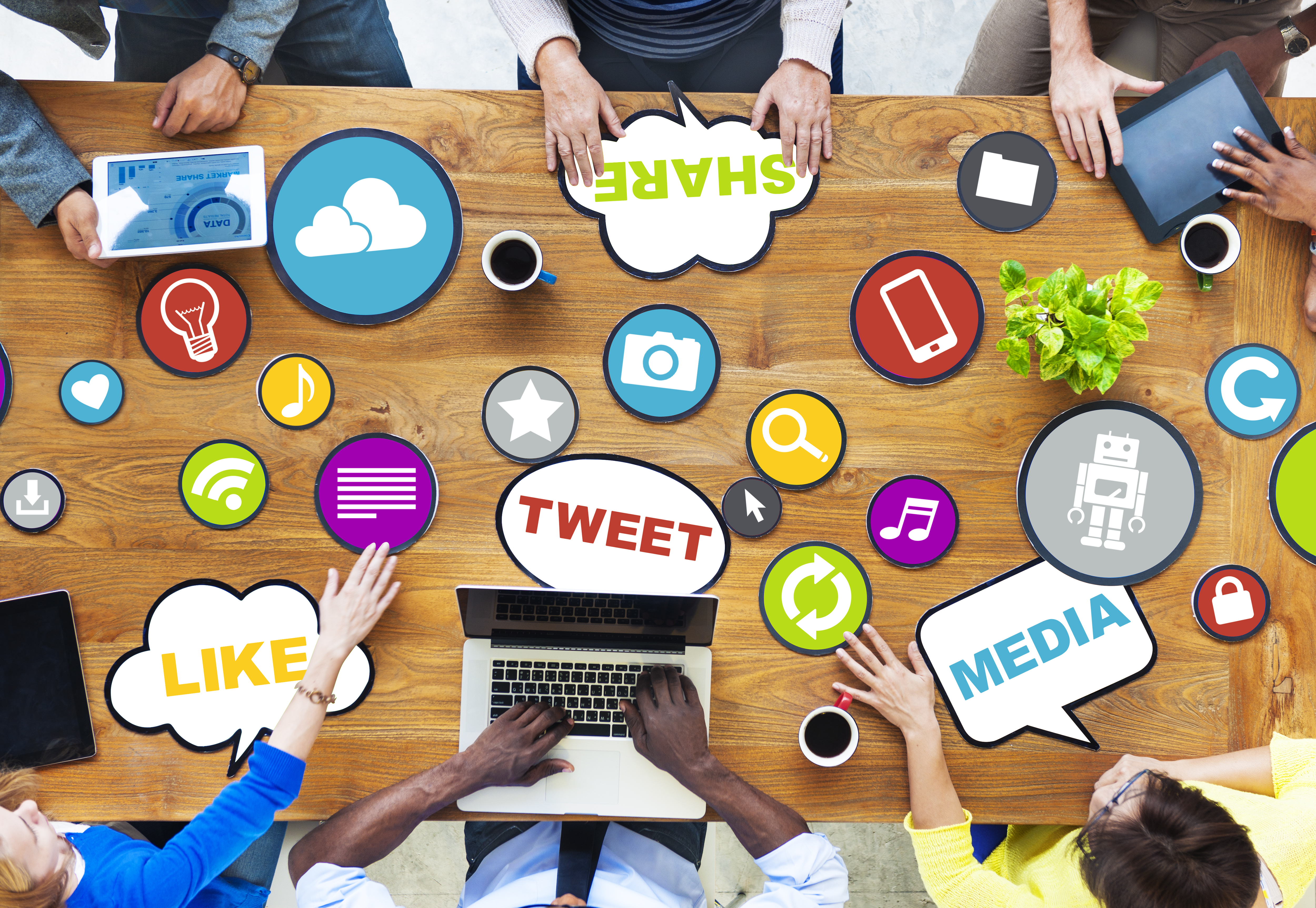 Stock photo showing elements of social media marketing like 'share', 'media', 'tweet', and 'like' on a table surrounded by a team of people.